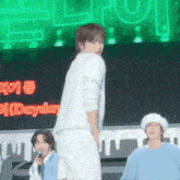 a man in a white shirt is standing on a stage in front of a green screen .