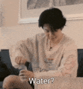 a person sitting on a couch with a bottle of water in front of them and the word water written on the bottom