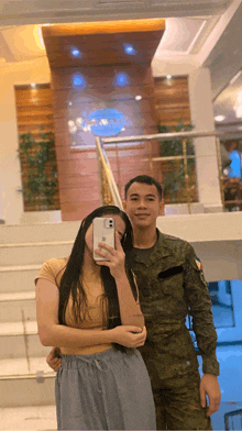 a man in a military uniform takes a selfie with his girlfriend