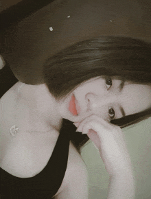 a woman wearing a black tank top and a silver necklace with a heart on it