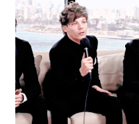 a man in a black suit is holding a microphone