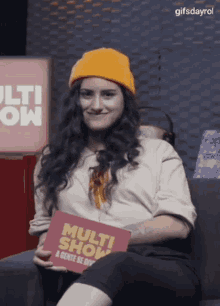 a woman is sitting on a couch holding a card that says multi show