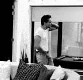 a man in a white t-shirt is standing in a living room