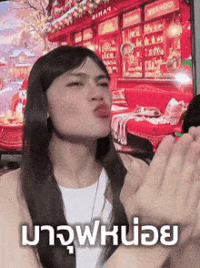 a woman blowing a kiss in front of a tv with a christmas background
