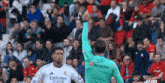 a soccer player wearing an emirates jersey is shown a red card by a referee