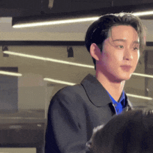 a young man in a black jacket and blue shirt