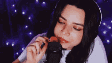 a woman wearing headphones is licking a microphone with her tongue