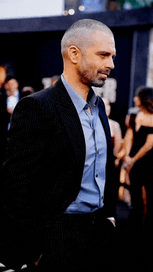 a man in a suit and blue shirt is standing in a crowd of people