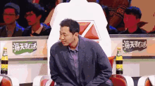 a man in a suit is sitting in front of a sign that says ' coca cola '