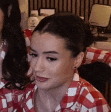 a woman in a red and white checkered shirt is sitting in front of a mirror .