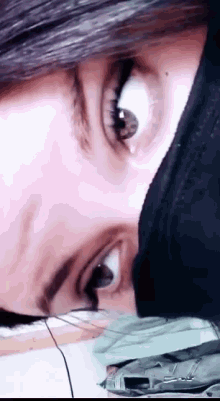 a close up of a woman 's eye with a black hood on