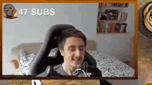 a man is sitting in a video game chair on a bed and smiling .
