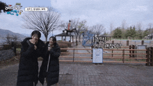 two women standing next to each other in a park with a sign that says tamago production