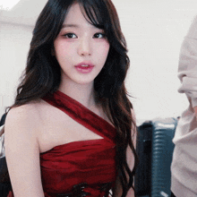 a woman in a red dress looks at the camera with a serious look on her face
