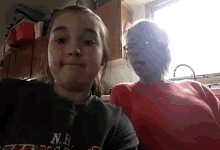 a girl wearing a nh sweatshirt sits next to an older woman in a kitchen