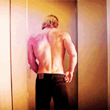 a shirtless man standing in front of a door