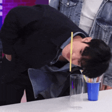 a young man is drinking through a straw from a blue cup