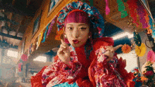 a woman with pink hair and a colorful dress is standing in a room .
