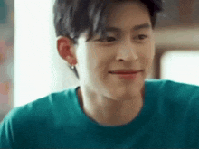 a close up of a young man wearing a blue t-shirt and earrings .