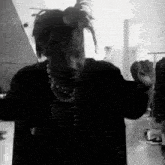 a man with dreadlocks is standing in a room with his arms outstretched .