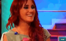 a woman with red hair is smiling in front of a screen that says rtd.gif