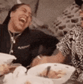 a woman is laughing while sitting at a table with food .