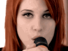 a close up of a woman holding a microphone in her mouth .