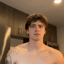 a shirtless man with a tattoo on his chest is making a funny face in a kitchen .