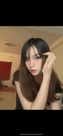 a girl with long black hair is looking at the camera and touching her hair