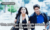 a man and a woman are walking down a street and the woman is saying `` okay , you 're on .