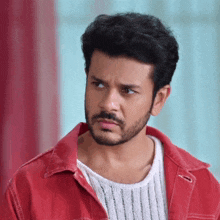 a man with a beard is wearing a red jacket and white sweater