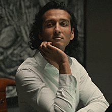 a man in a white shirt has his hand on his face