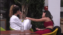two women are sitting at a table talking to each other .