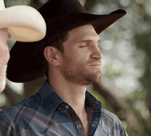 a man wearing a cowboy hat and a plaid shirt