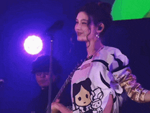 a woman wearing a shirt with a girl on it stands in front of a microphone on a stage