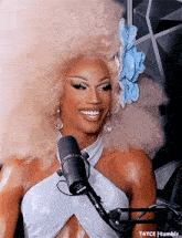 a woman with a flower in her hair is smiling in front of a microphone
