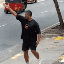 a man in a black shirt is walking down a sidewalk while a red rickshaw is driving behind him .