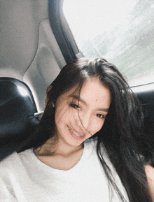 a woman with braces on her teeth is smiling in a car