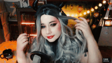 a woman wearing horns and headphones looks at herself in a mirror