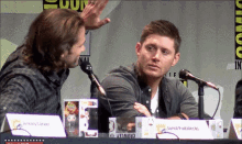 two men sitting at a table with a name tag that says " jared padalecki "