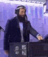 a man with a beard is wearing headphones and a headband while standing in front of a microphone .