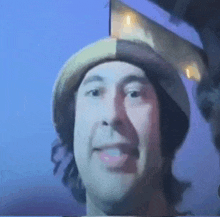 a man wearing a hat is smiling and sticking out his tongue