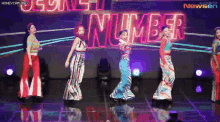 a group of young women are dancing on a stage in front of a neon sign that says number .