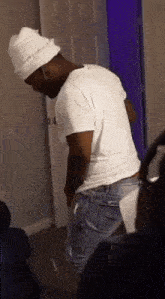 a man wearing a white hat is standing in a room .