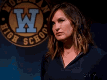 a woman stands in front of a school logo