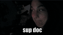 a woman is making a funny face with the words sup doc behind her