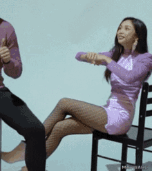 a woman in a purple dress is sitting on a chair next to a man