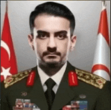 a man in a military uniform is standing in front of a flag .