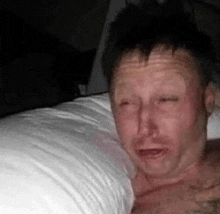a man is laying on a bed with his eyes closed and his mouth open .