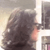 a man with long curly hair is wearing sunglasses and a black shirt .